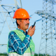 Low angle of professional electrician technician in hardhat and waistcoat speaking on portable radio